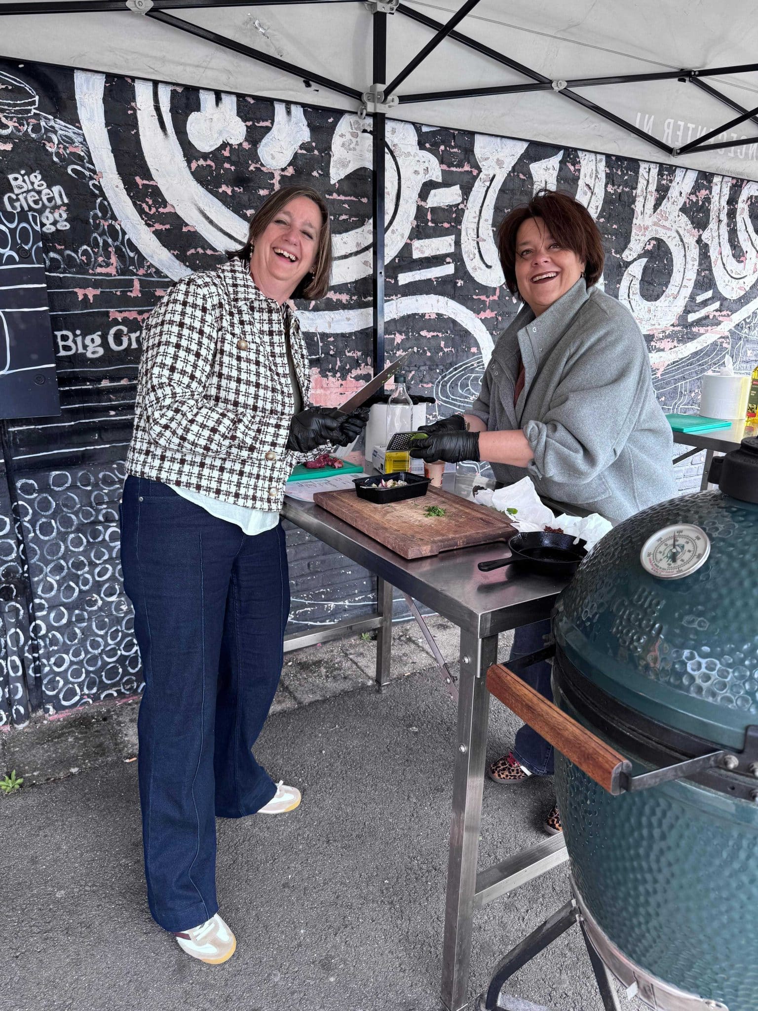 Twee bezoekers lachen tijdens het koken op de Big Green Egg